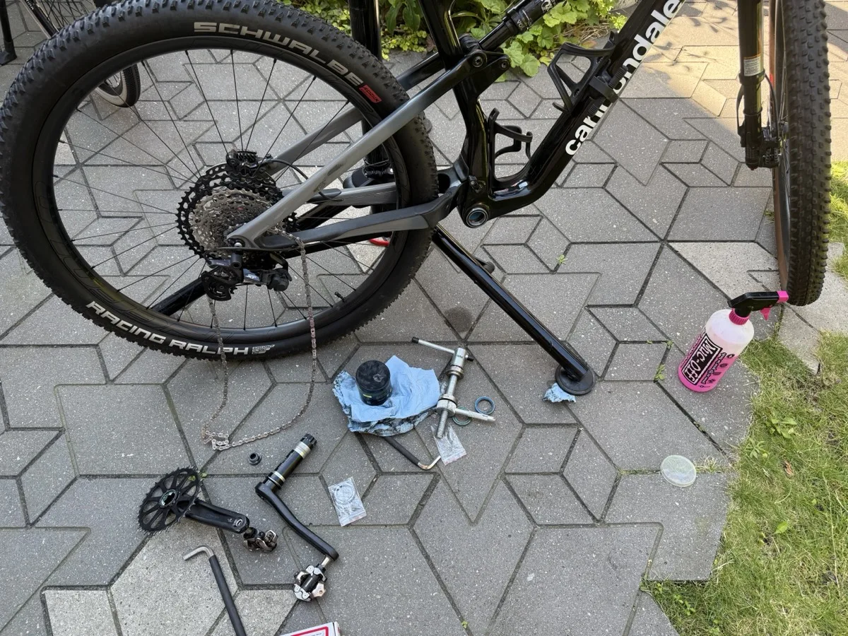 Cannondale Scalpel on its kickstand with the crankarm removed, a Park Tool RT-1 remover and the old BB30 bearing on the paving, and the new bearing still in its bag