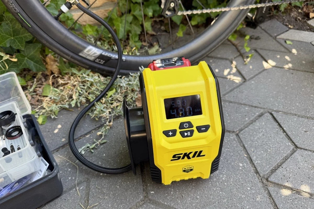 The yellow SKIL 3159 VL inflator on a patio beside a Vision Team 40 TLR wheel, LCD showing 4.80 BAR live against a 5.90 target